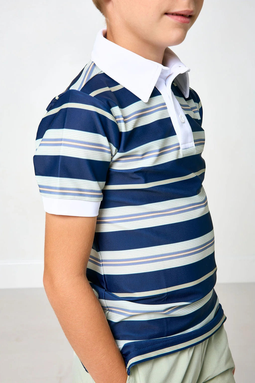 A child wearing a short-sleeve polo shirt with horizontal navy, white, and light blue stripes, paired with a white collar and light khaki pants.