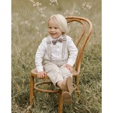 toddler boy wearing white long sleeve button down collared shirt with suspenders and bowtie
