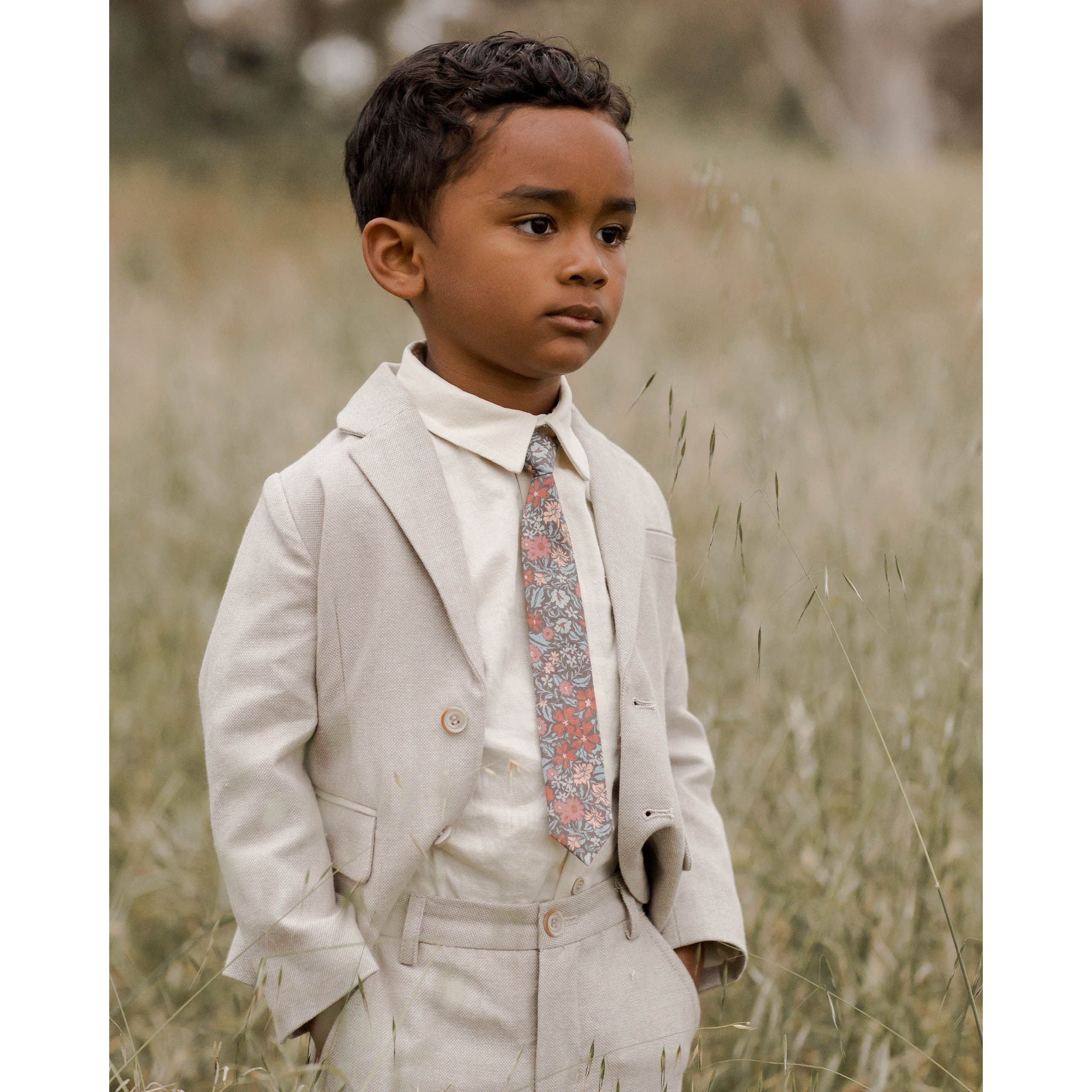 boy wearing navy colored skinny tie with berry garden floral print with linen suit and white button down