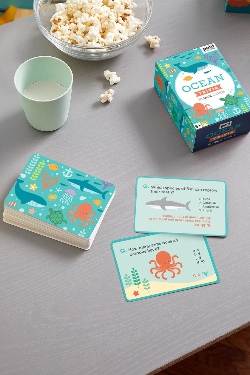 Ocean-themed card game with cards, a cup, and popcorn on a gray surface