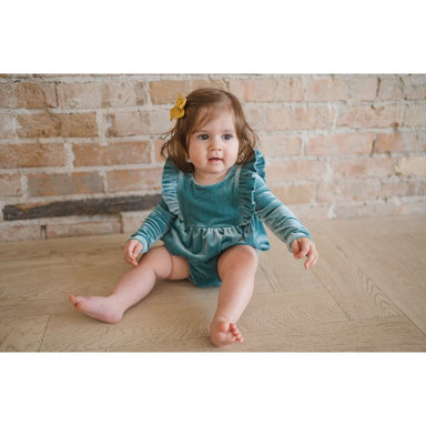 toddler girl wearing blue/green velvet long sleeve bubble romper with ruffle detail in front and back