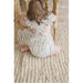back view of baby girl wearing white ruffle sleeve bubble with floral print