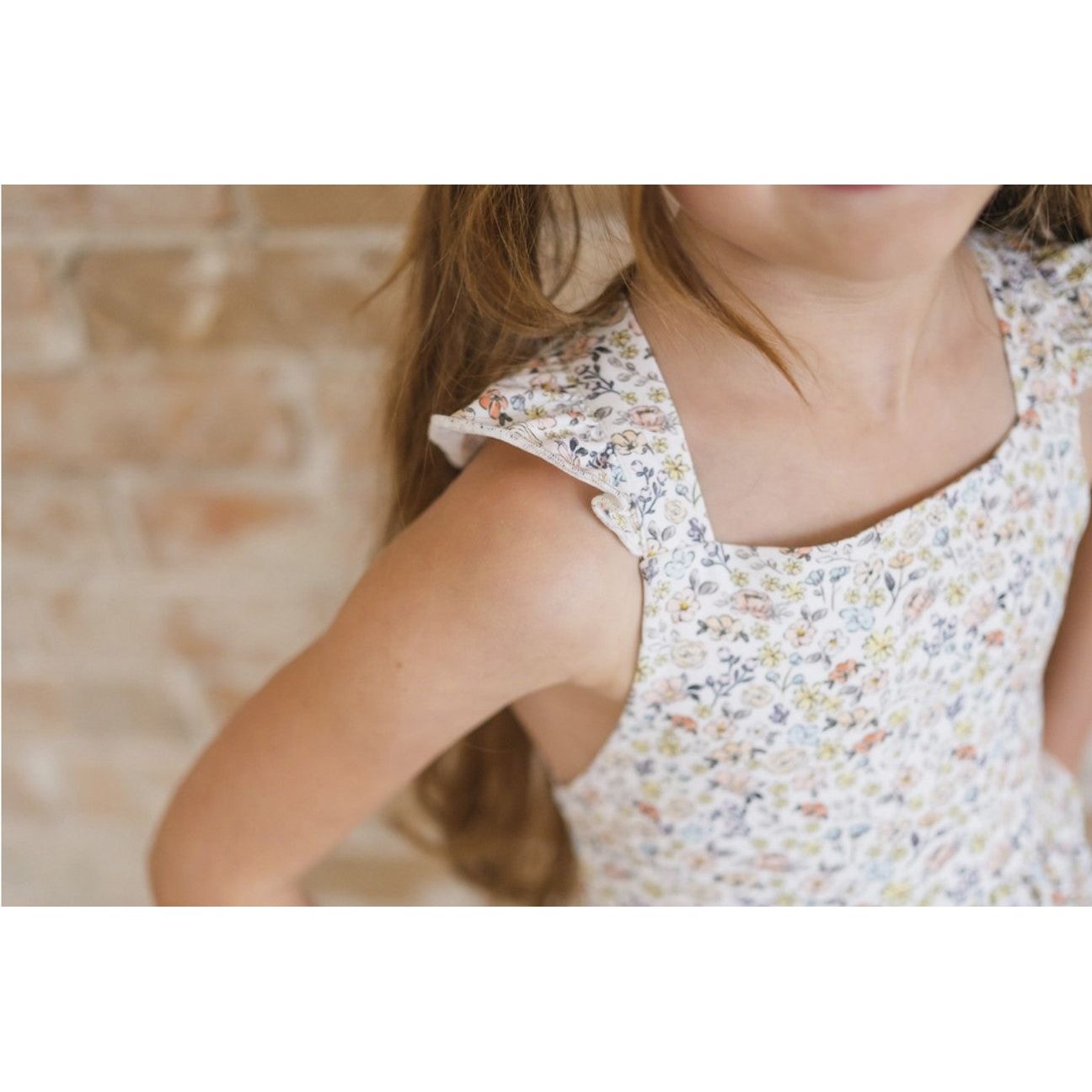 up close of girl wearing white twirl dress with flutter sleeves and floral print