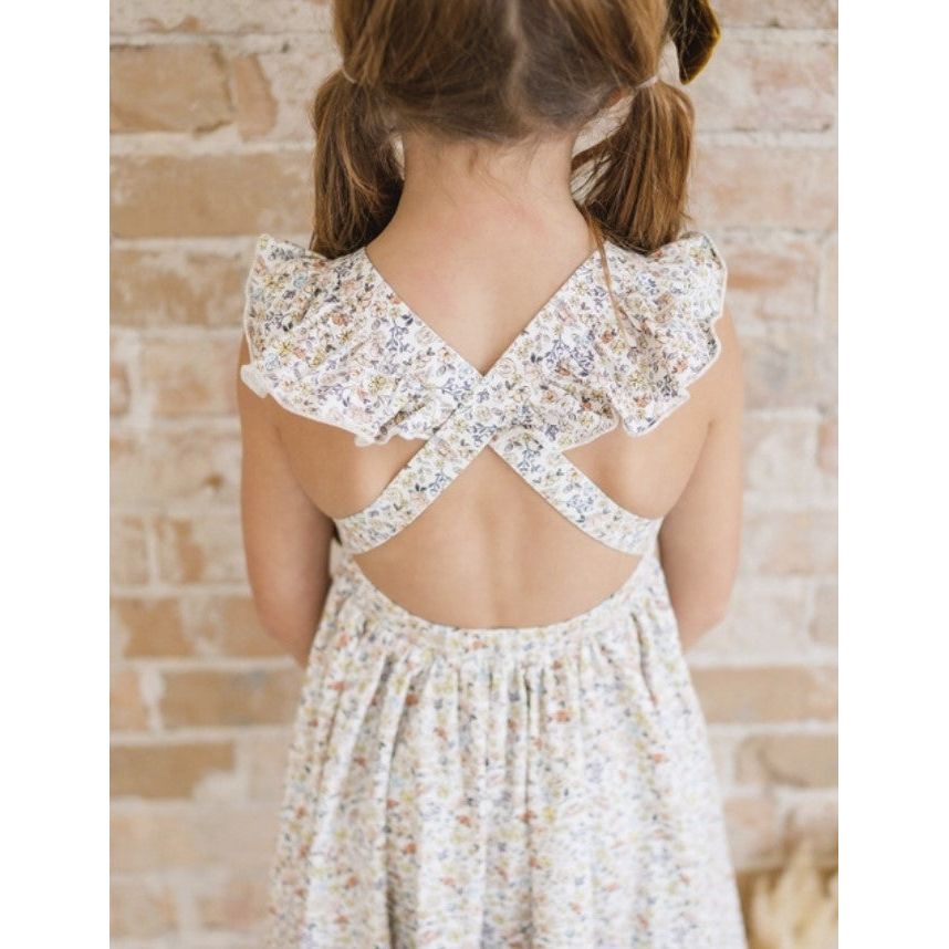 back view of girl wearing white twirl dress with criss cross back detail and floral print