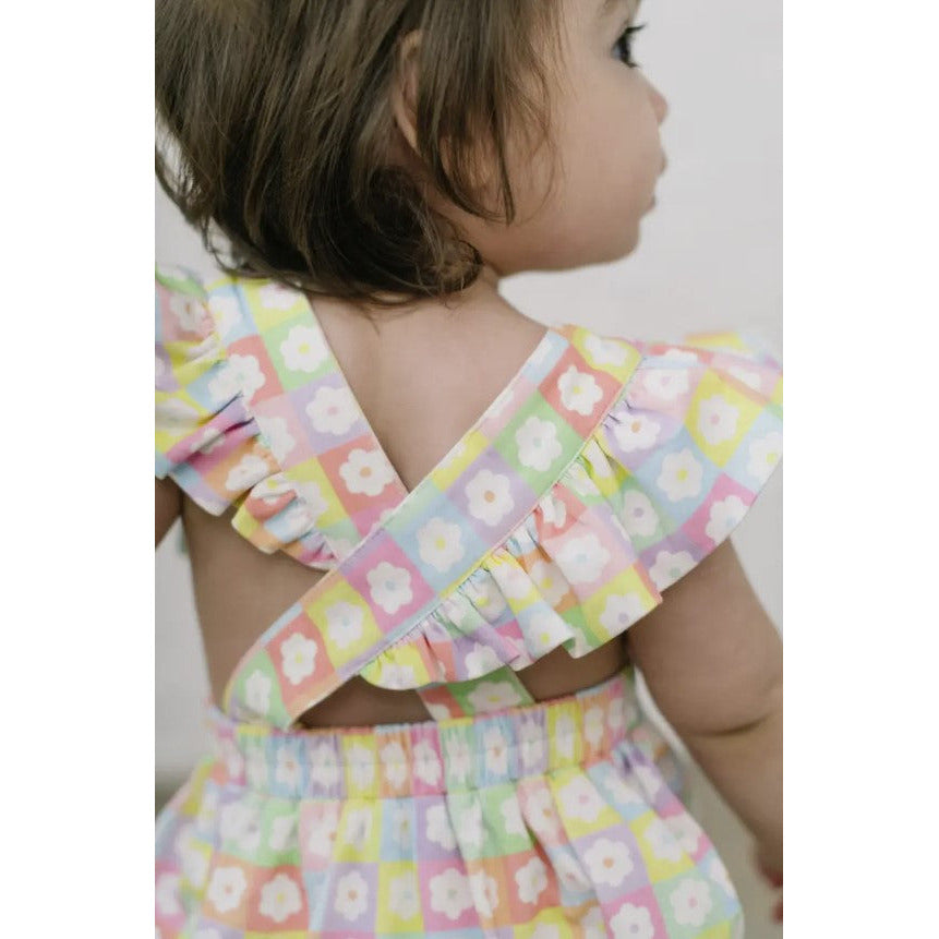 toddler wearing multicolor floral bubble romper with flutter sleeves and criss cross back detail