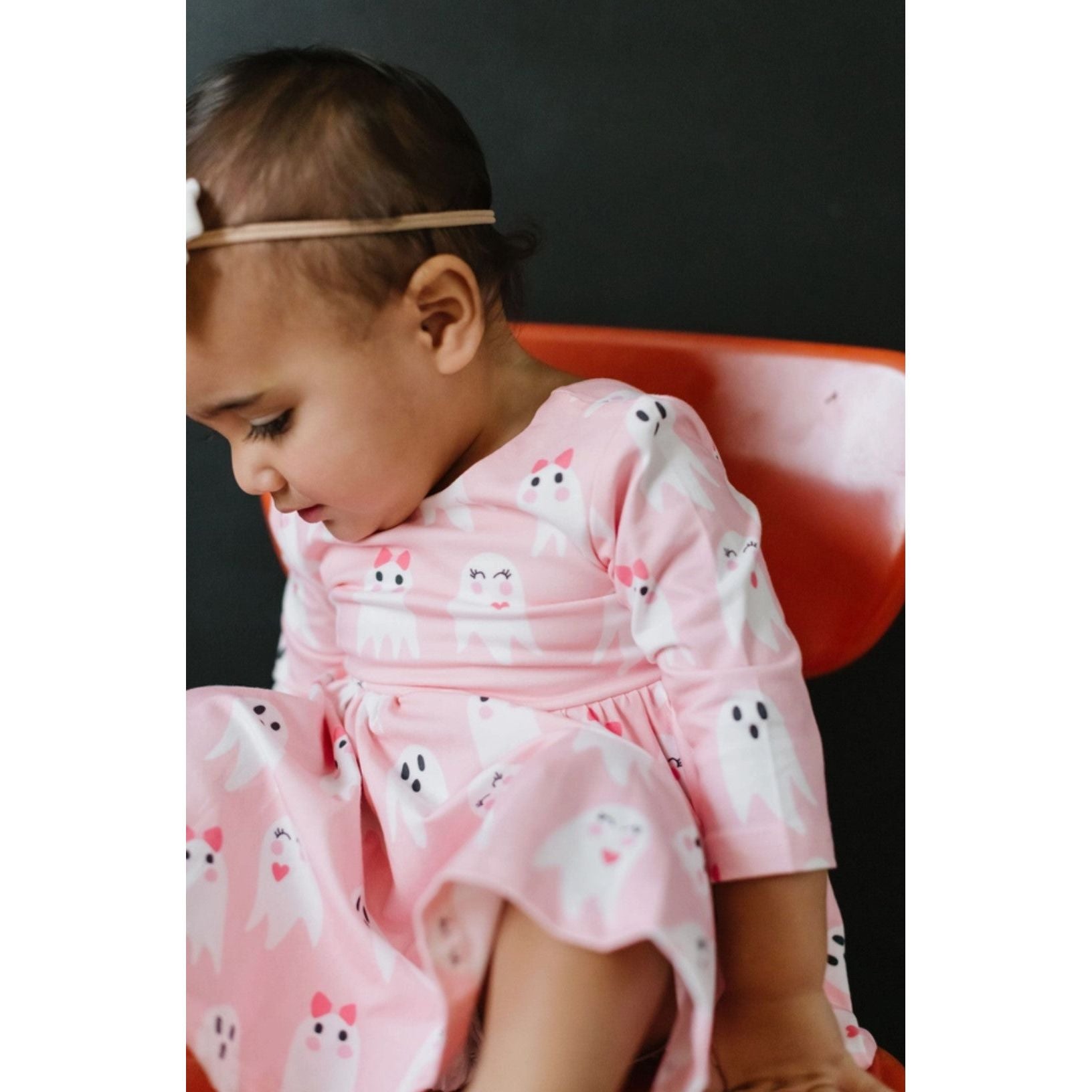 up close of toddler girl wearing 3/4 length sleeve pink dress with girly ghost print