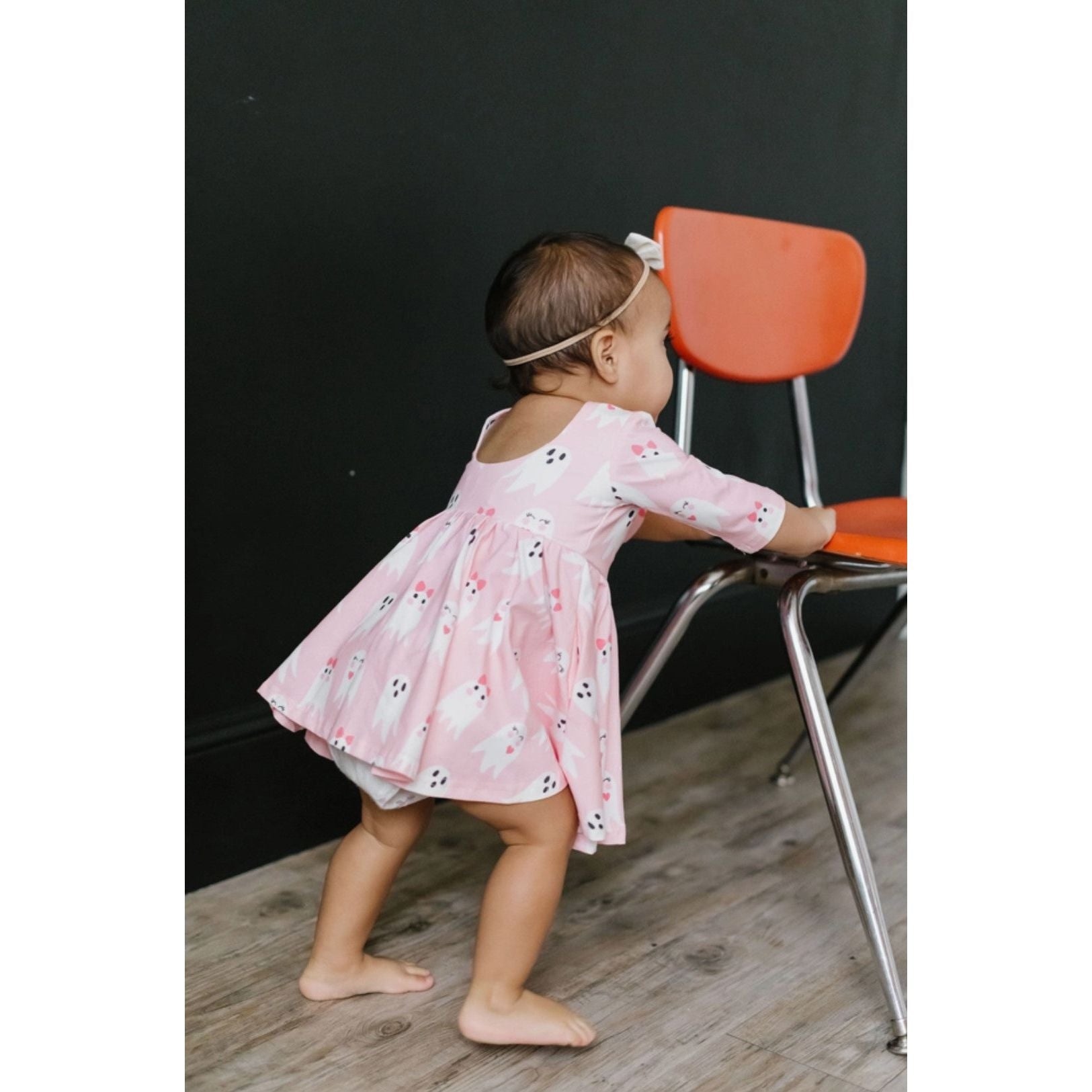 back view of toddler girl wearing 3/4 length sleeve pink dress with girly ghost print
