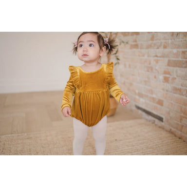 toddler girl wearing golden yellow velvet long sleeve bubble romper with ruffle detail in front and back