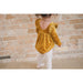 back of toddler girl wearing golden yellow velvet long sleeve bubble romper with ruffle detail in front and back