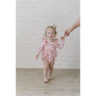 baby girl wearing white long sleeve ruffled bubble romper with multicolored hearts print