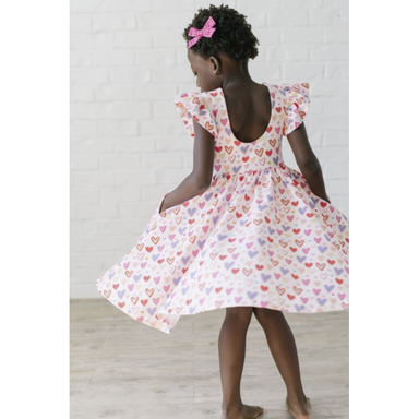girl wearing white ruffle sleeve twirl dress with multicolored hearts print