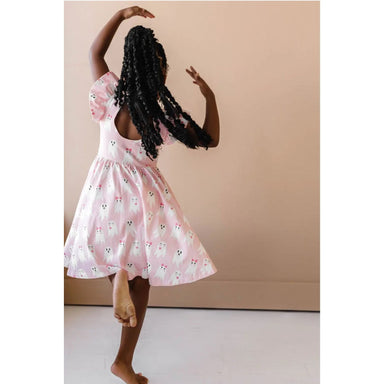 back view of girl twirling in pink ruffle short sleeve dress with girly ghost print with scoop back detail