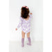 back view of toddler girl wearing purple ruffle long sleeved bubble romper with girly ghost print and scoop back detail