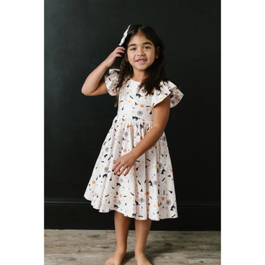 front view of girl wearing white ruffle short sleeve dress with spooky sccenes print