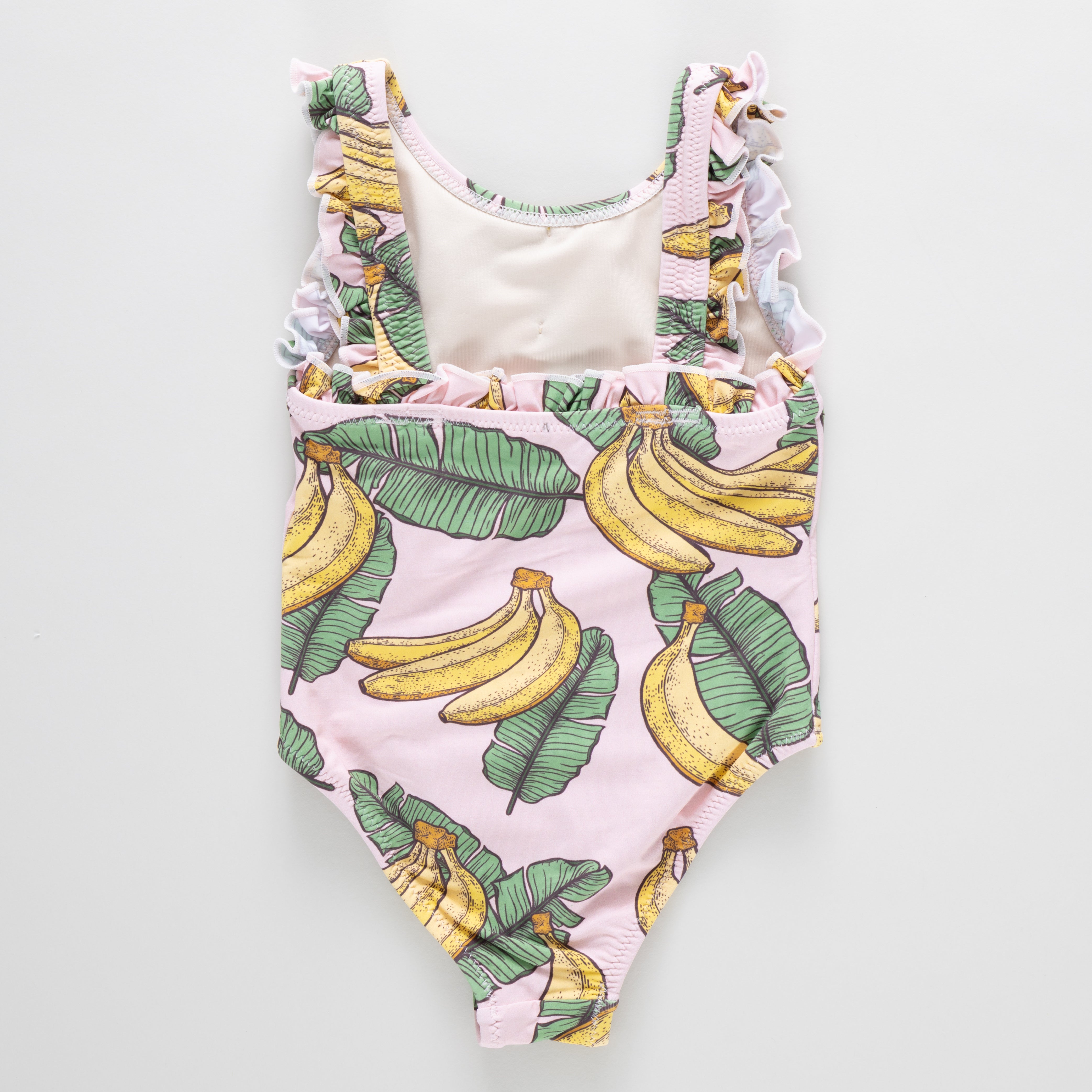One-piece swimsuit with banana and leaf pattern on a light gray background