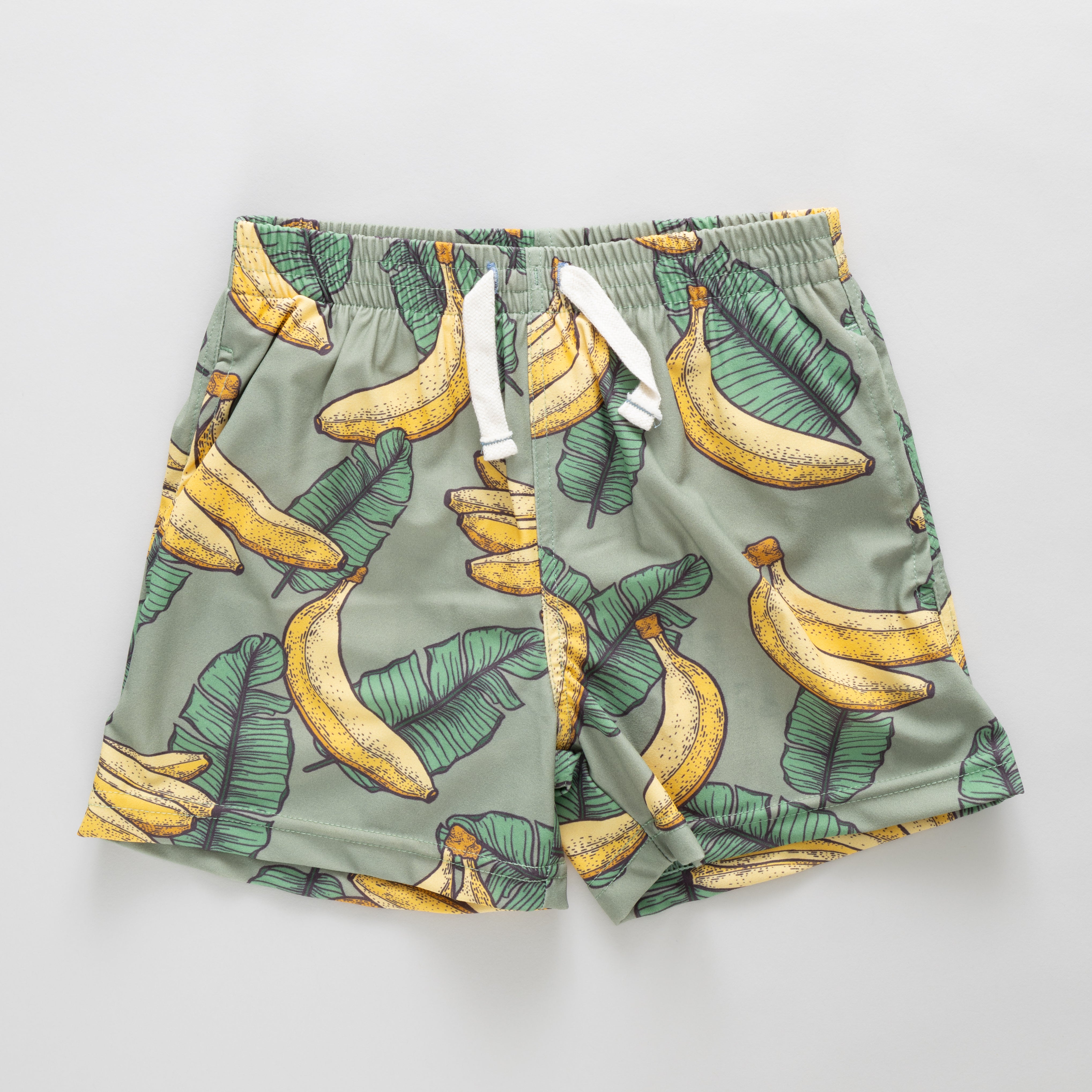 Green swim trunks with banana pattern on a light gray background