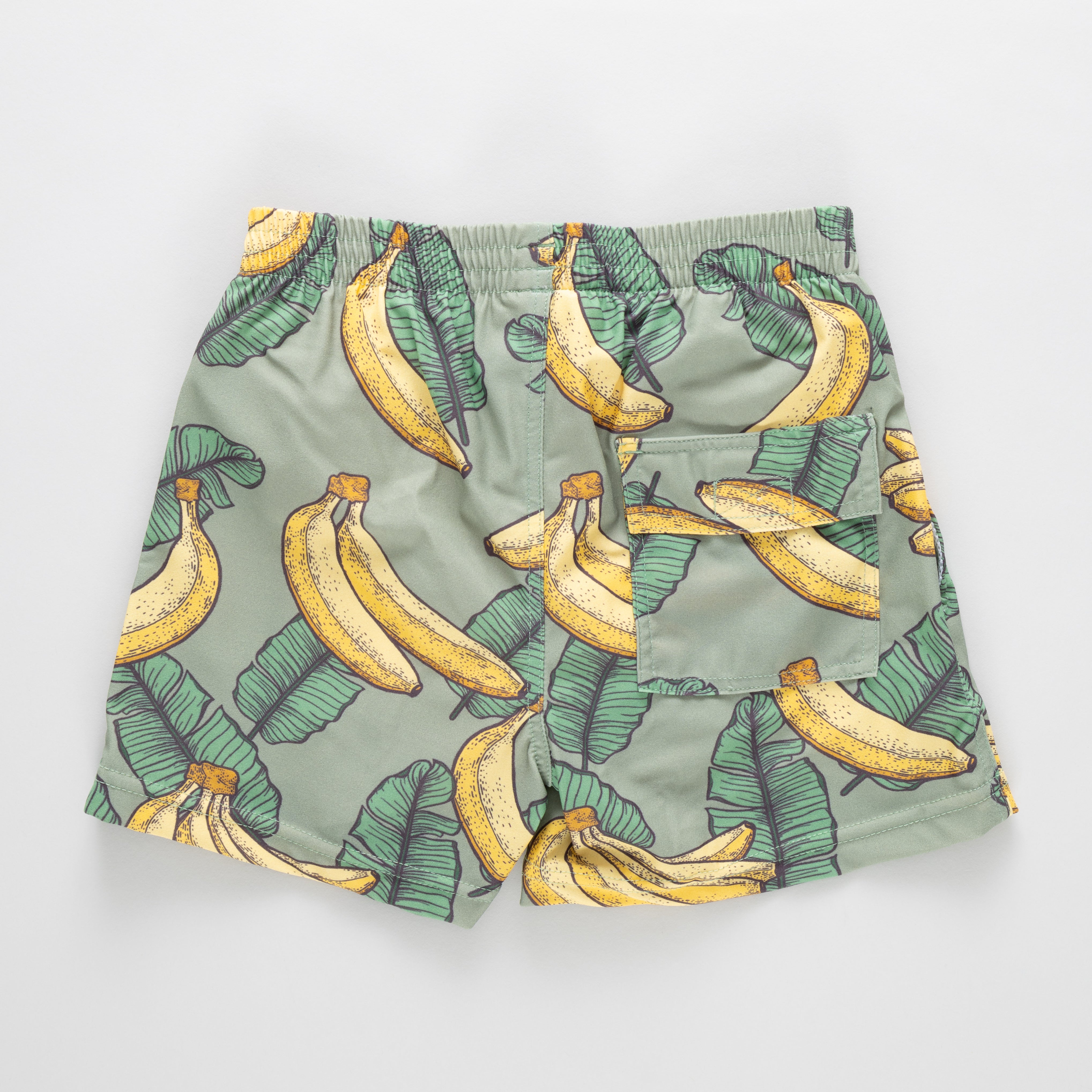 Green swim trunk with banana pattern on a light gray background
