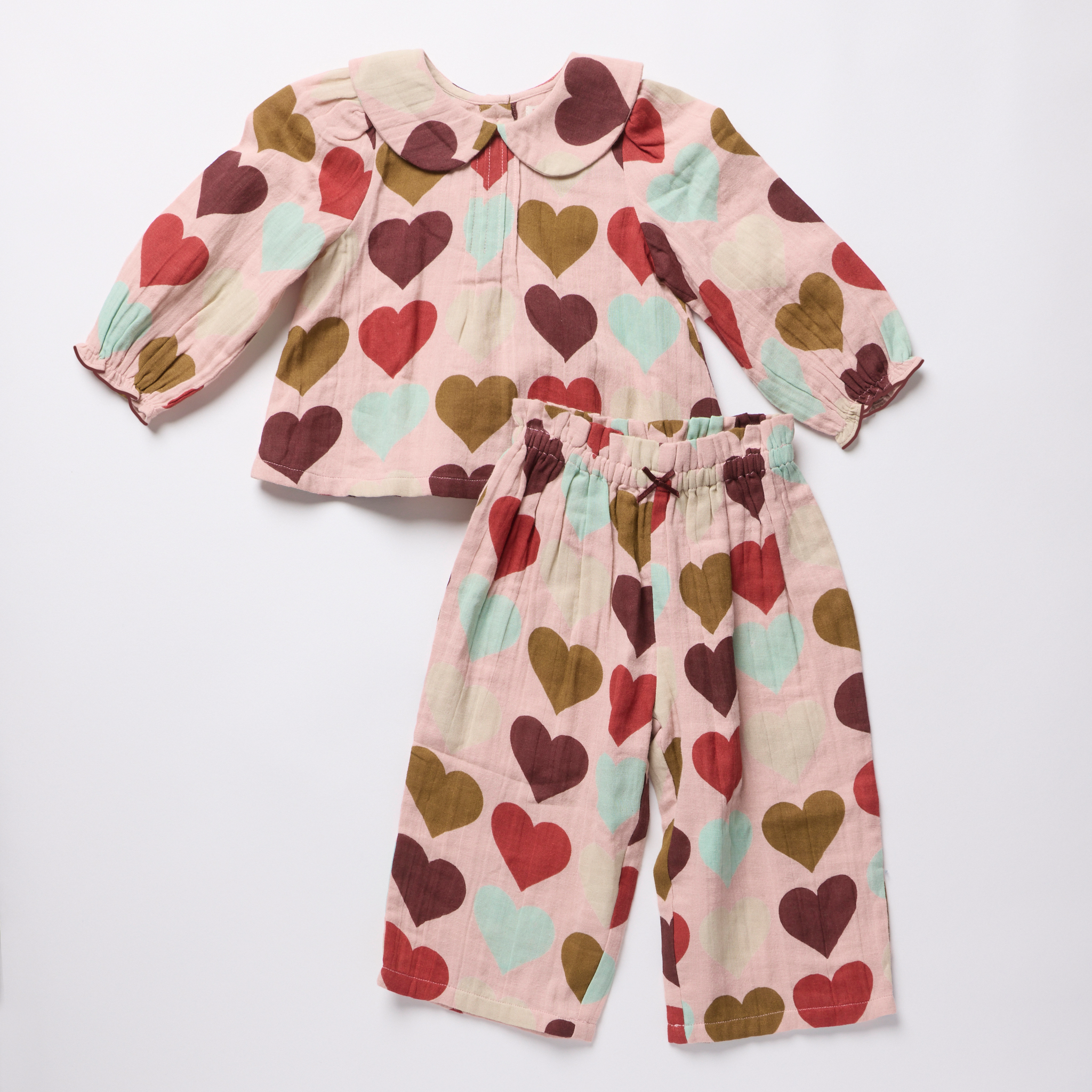 Pink Chicken baby girls two piece outfit with a soft pink top and matching pants featuring burgundy olive and seafoam hearts and a Peter Pan collar
