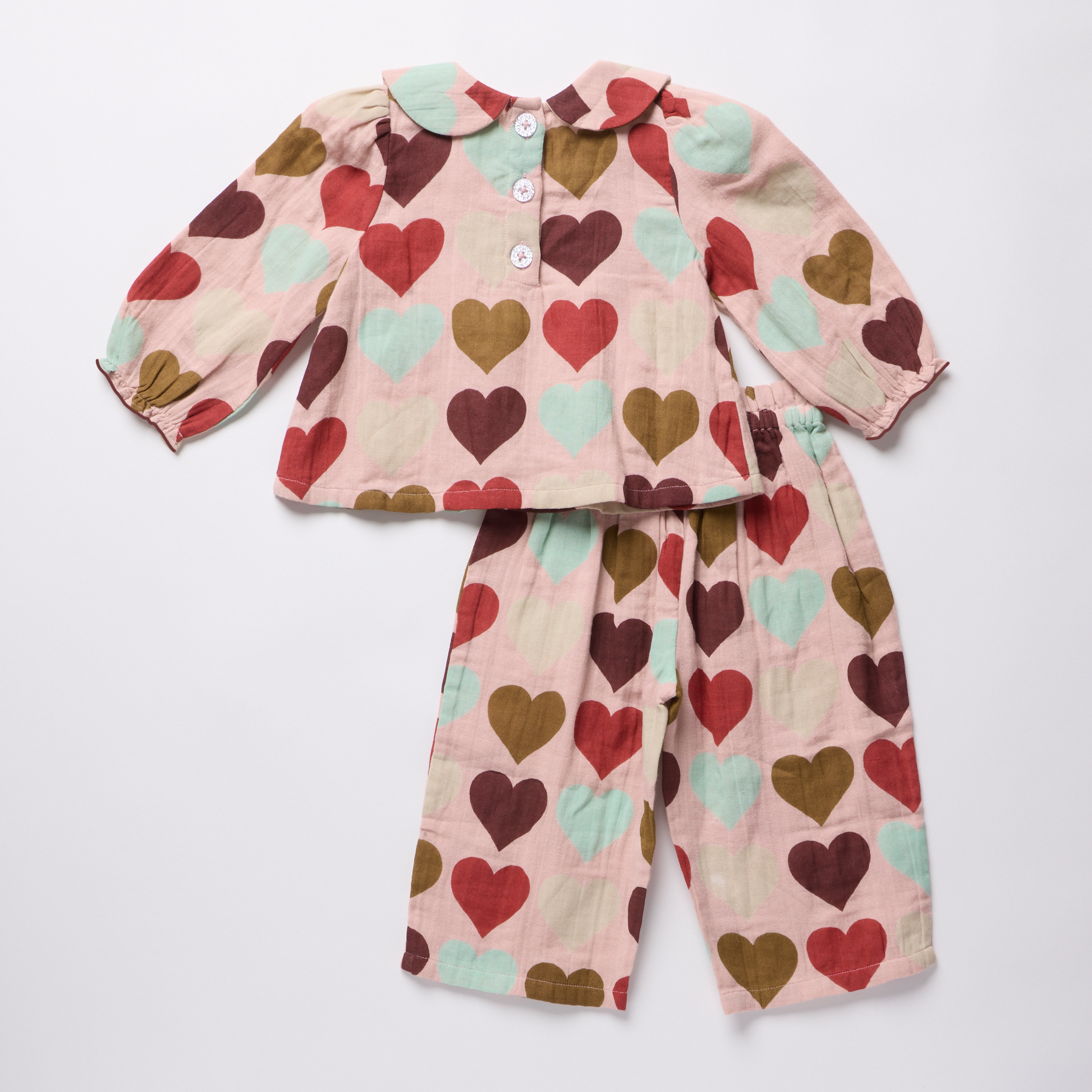 Pink Chicken baby girls two piece outfit with a Peter Pan collar and pintuck detail featuring multicolor hearts on a soft pink background with coordinating pants
