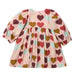 A children's long-sleeve dress with a gathered waist and an allover heart print on a light pink base, featuring red, brown, and mint green hearts. The dress is laid flat against a clean white background.