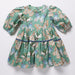 Green girls dress with puff sleeves and tiered skirt covered in colorful butterfly prints from Pink Chicken