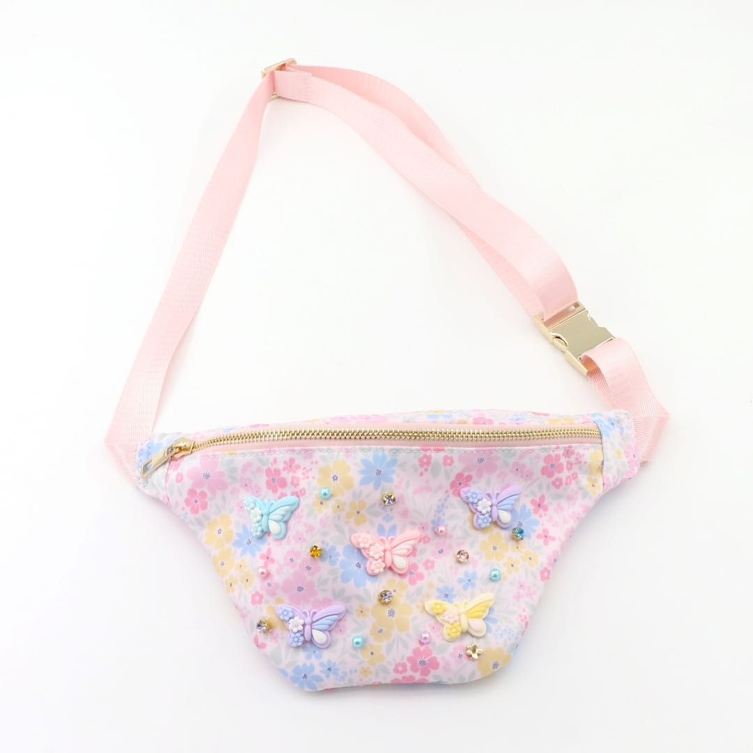Pastel floral and butterfly patterned fanny pack with pink strap on a white background