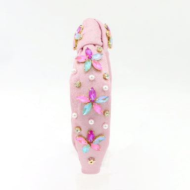 Pink hair tie with floral and bead decorations on a white background