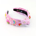 Pink sleep mask with rainbow design and decorative elements on a white background