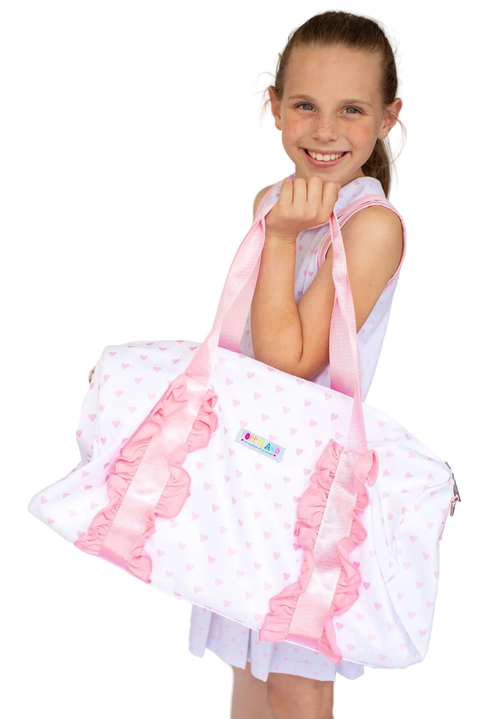 Young girl holding a large pink and white bag with ruffles on a plain background