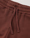 Close-up of a pair of brown sweatpants showing the elastic waistband and matching drawstring.