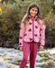 A girl next to a stream wearing a pink jacket with dark pink hearts pattern