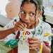 Child drinking from a straw with a colorful shirt and balloons in the background