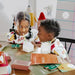 Two children sitting at a table with educational materials, engaged in learning.