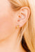 Close-up of an ear wearing a pencil earring with blonde hair.