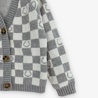 up close view of gray and white checkered cardigan with horseshoes