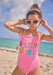 Young girl in a pink swimsuit with 'B-Day Girl' text on a beach