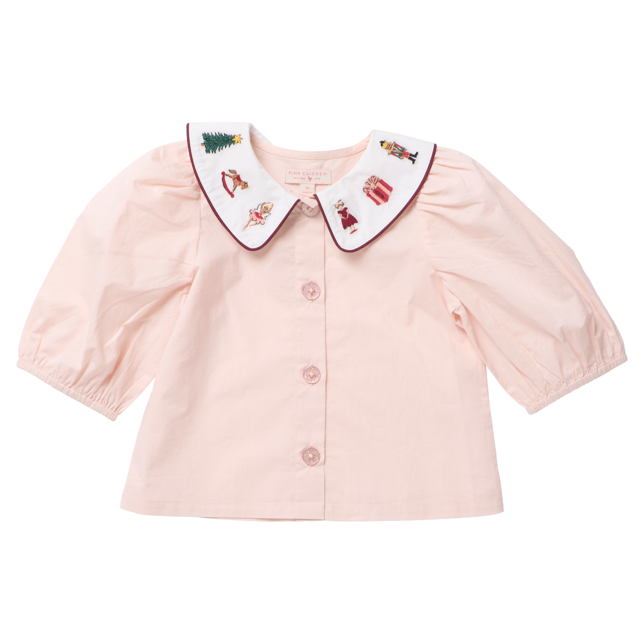 A baby girl's light pink blouse with a white Peter Pan collar featuring embroidered holiday characters, shown on a plain white background.