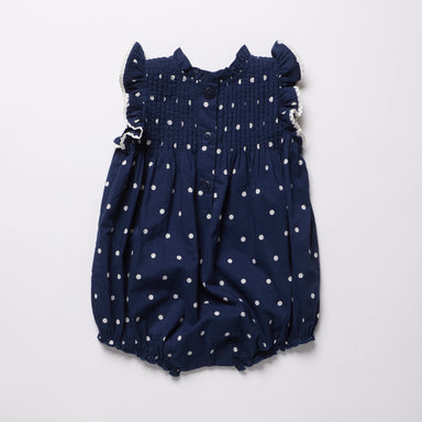 Navy blue romper with white polka dots on a light gray background