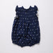 Navy blue romper with white polka dots on a light gray background