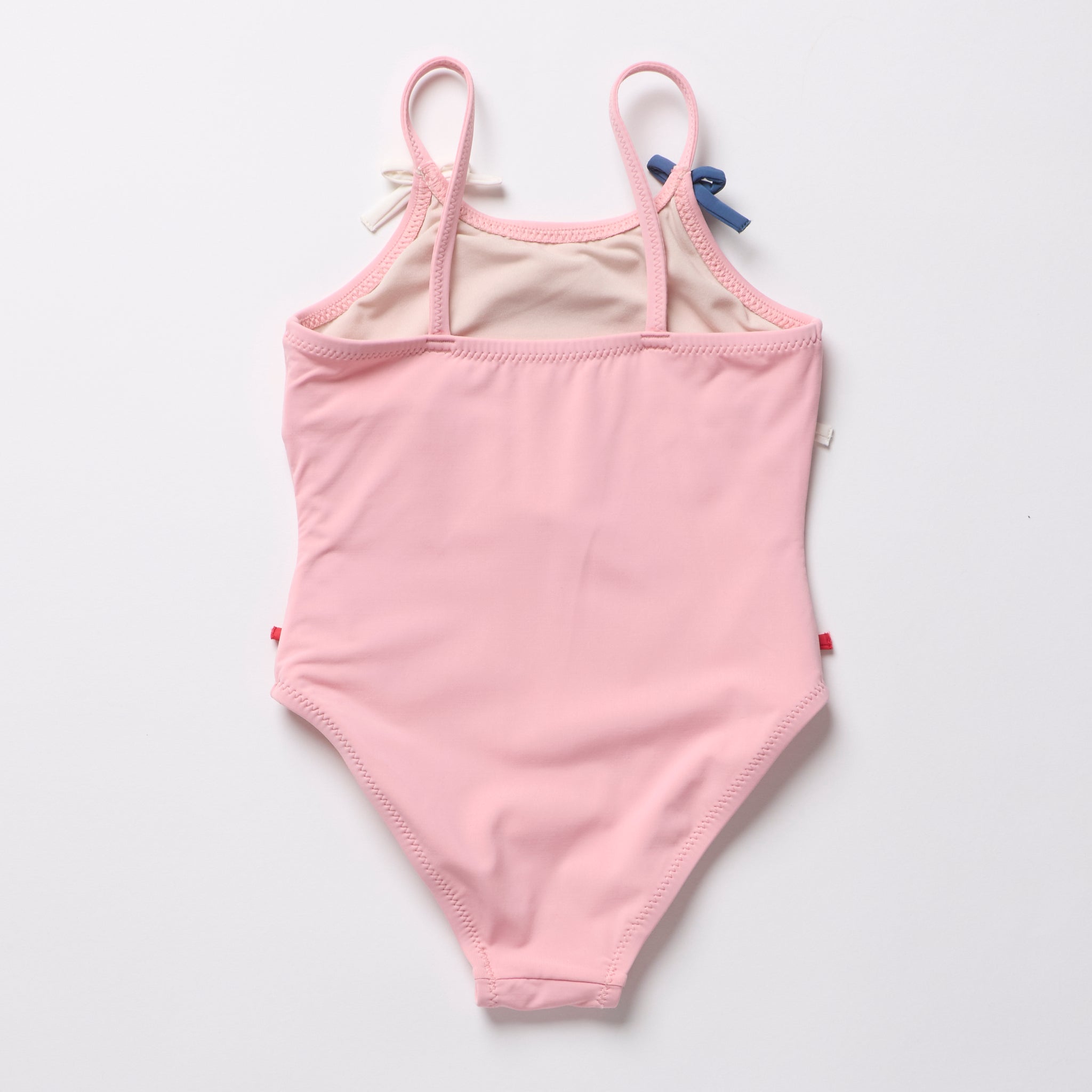 Pink children's swimsuit with white lining on a light gray background