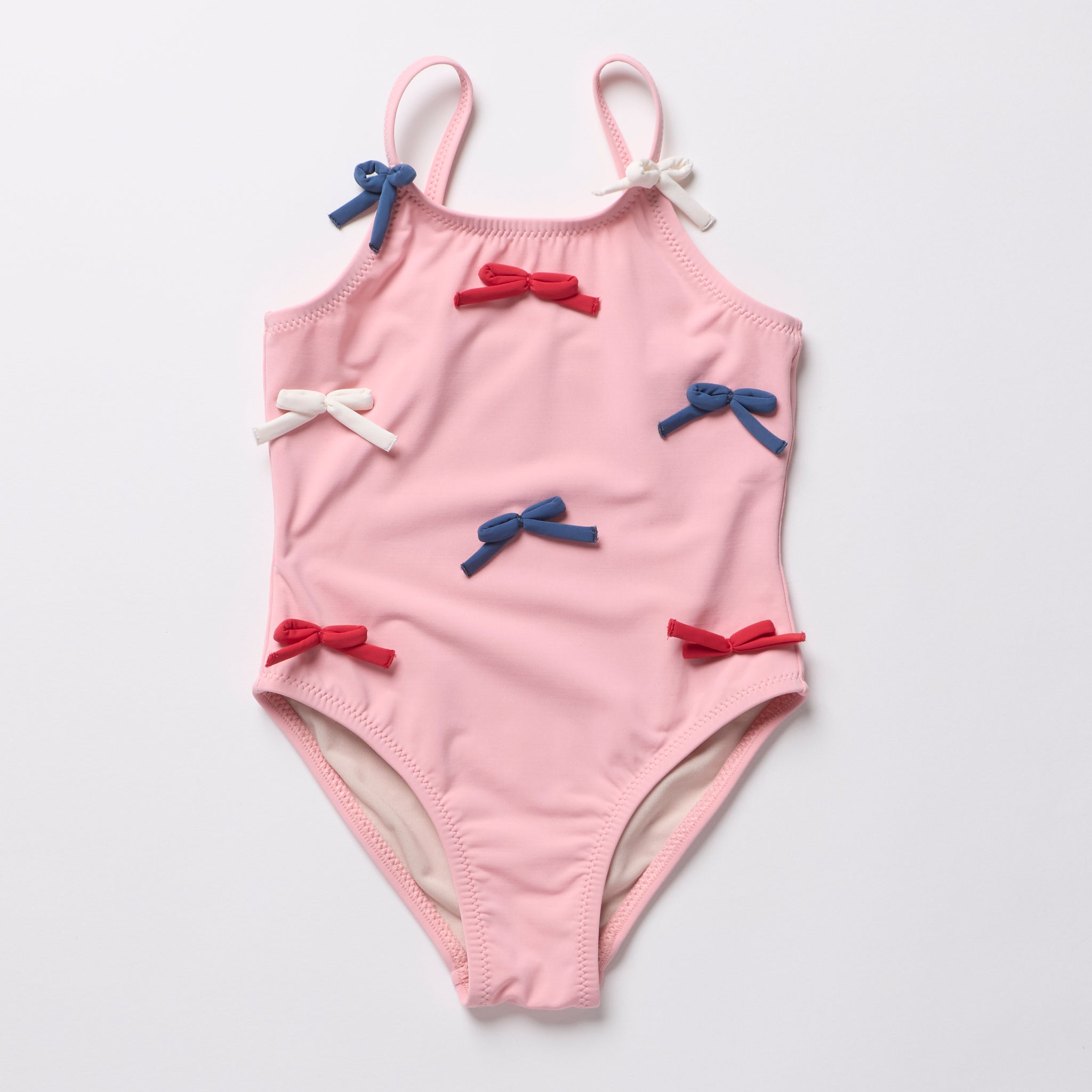Pink children's swimsuit with bow details on a light gray background