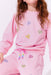 Child wearing a pink outfit with heart patterns on a white background