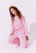 Young girl wearing pink sweatsuit with heart patterns on a white background
