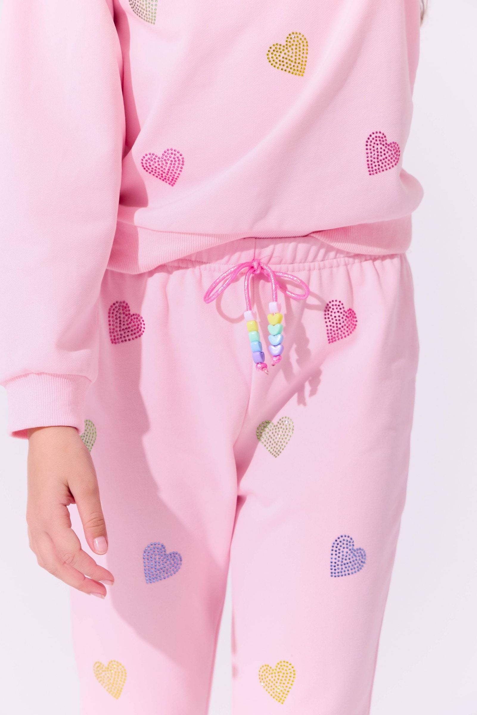 Pink sweatsuit with heart patterns on a light pink background