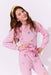Young girl wearing a pink outfit with heart patterns on a white background
