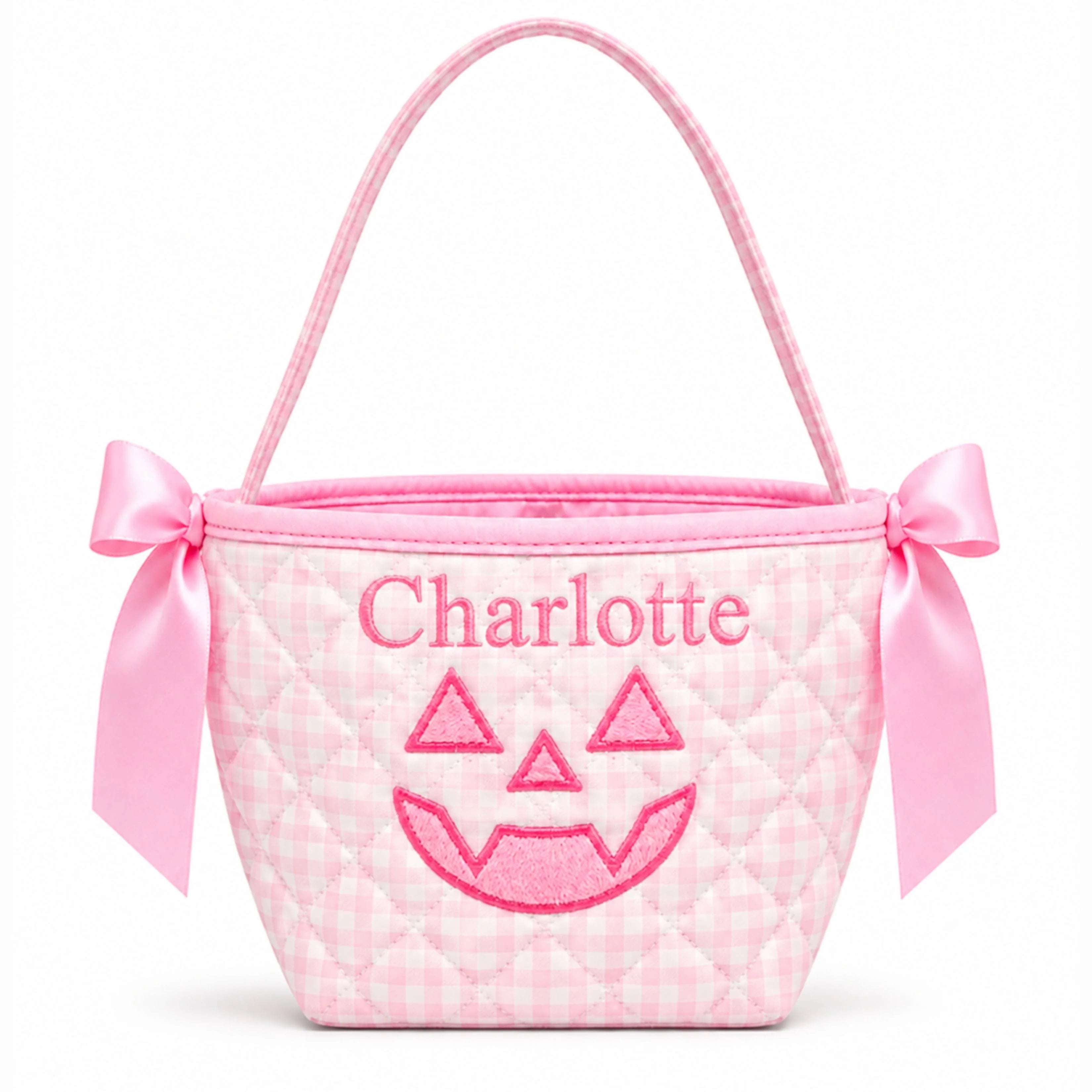 A pink gingham quilted mini bucket bag with a pink satin handle, bow details on the sides, and an embroidered jack-o'-lantern face and the name 'Charlotte' on the front.