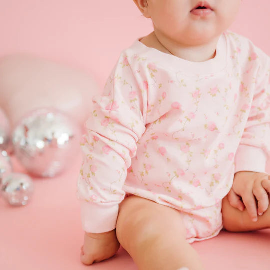 Baby in a pink outfit with floral patterns on a pink background