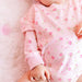 Baby in a pink floral outfit on a soft pink background