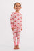 A young girl wearing a two-piece children's pajama set featuring a pink and white striped pattern with santa faces wearing red bows, complete with solid pink cuffs and collar.