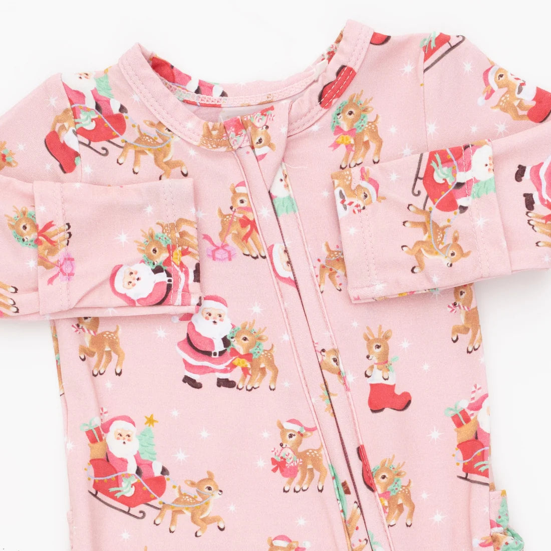A pink footed baby sleeper with a front zipper, decorated with a festive Christmas print featuring Santa Claus, reindeer, and snowflakes.